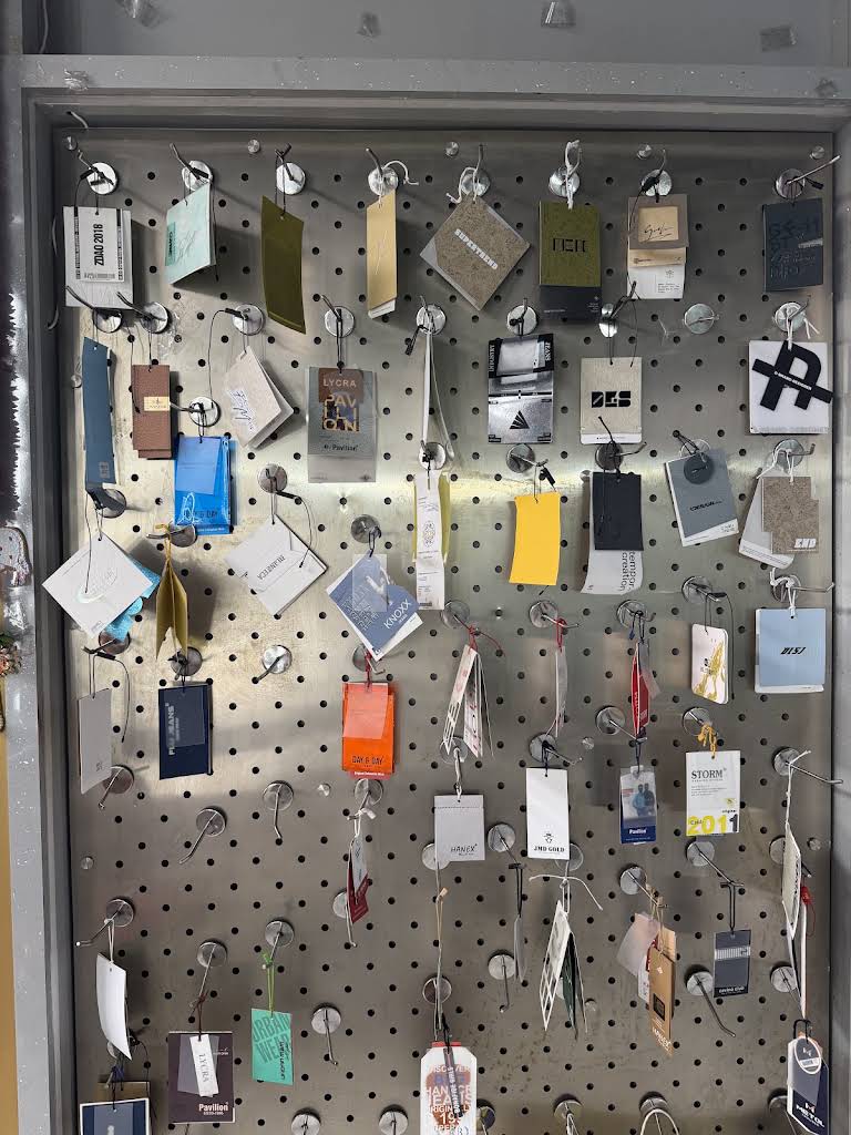 Garment accessory tags, trims and components arranged on the Lekha sample wall